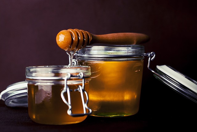 Two jars of golden honey with a honey dipper.