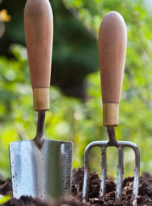 Two gardening tools stuck in dirt